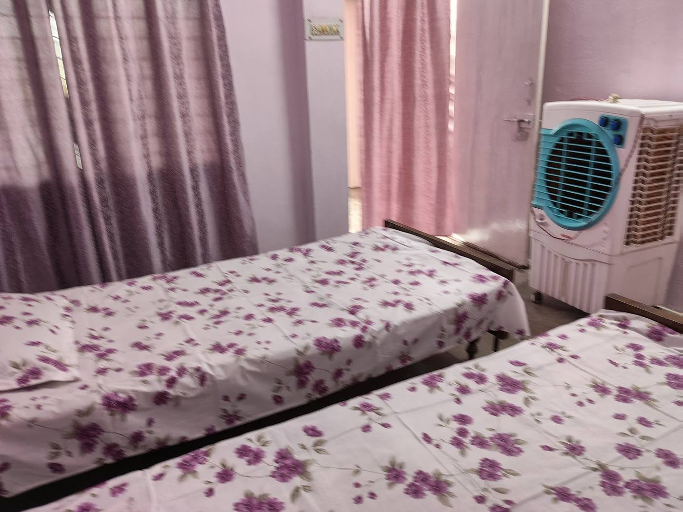 Twin room with floral sheets and a cooler