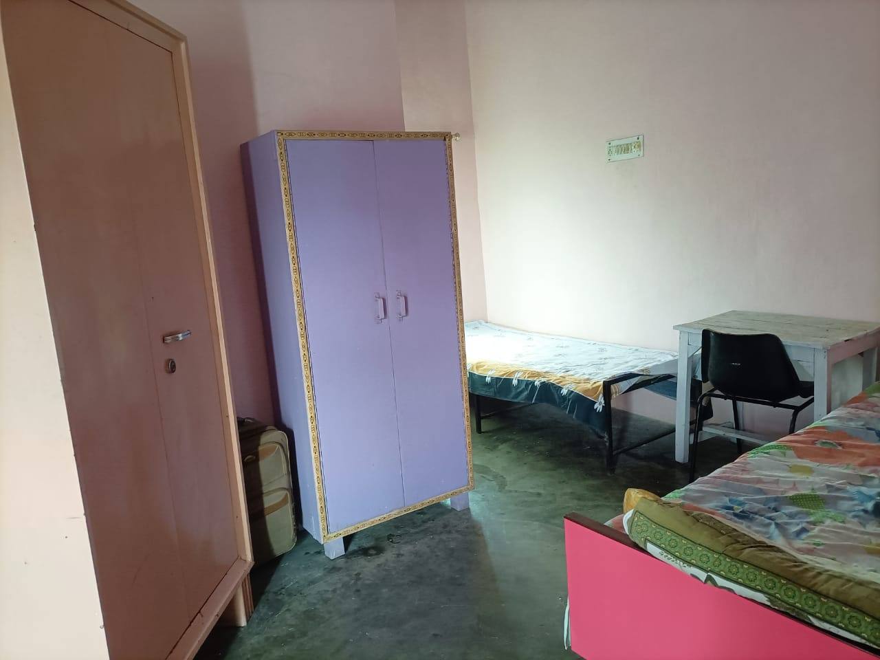 Room with a lavender wardrobe, beds and a study table