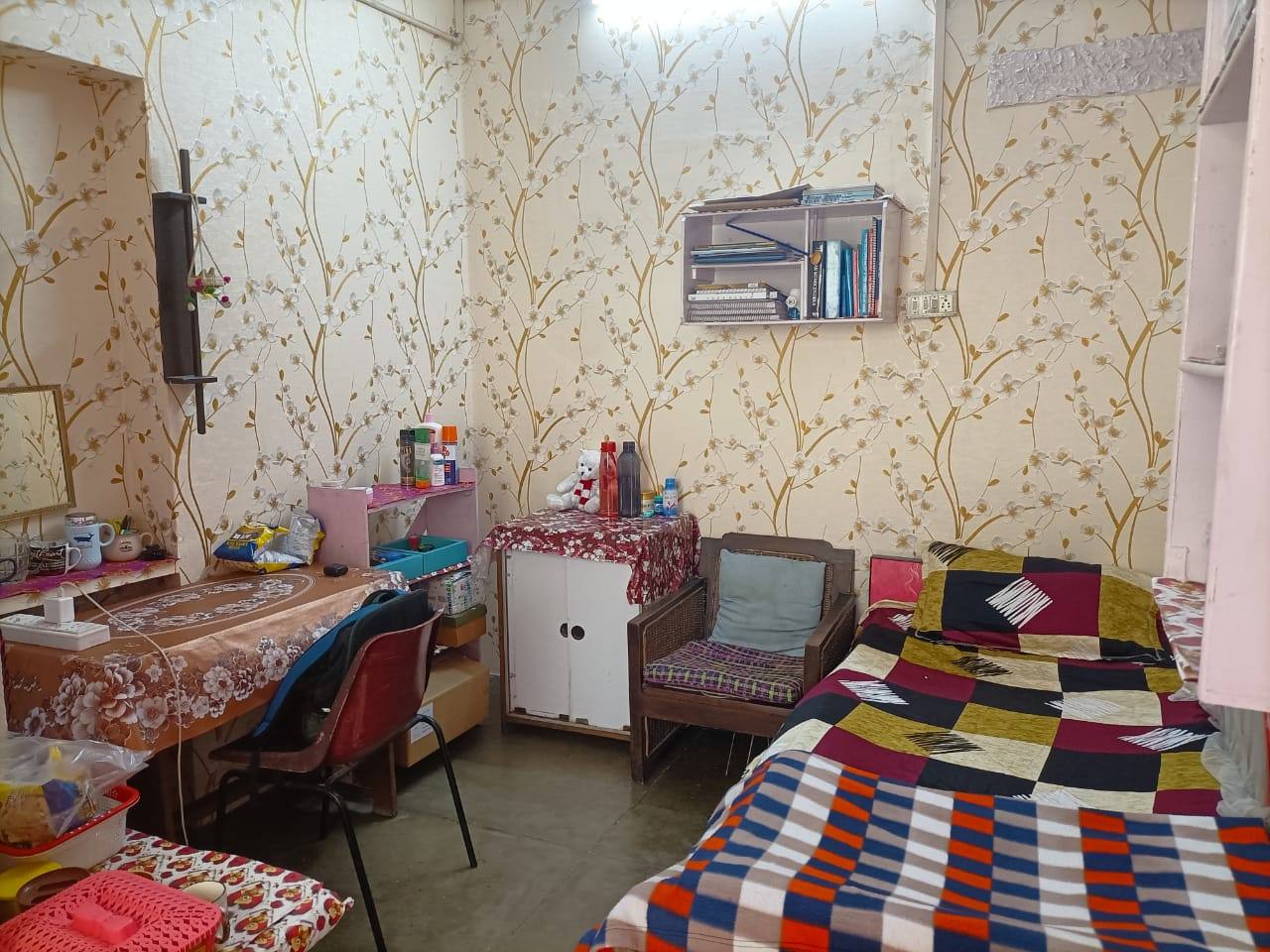 A lived-in room with a study desk, bookshelf and cupboard