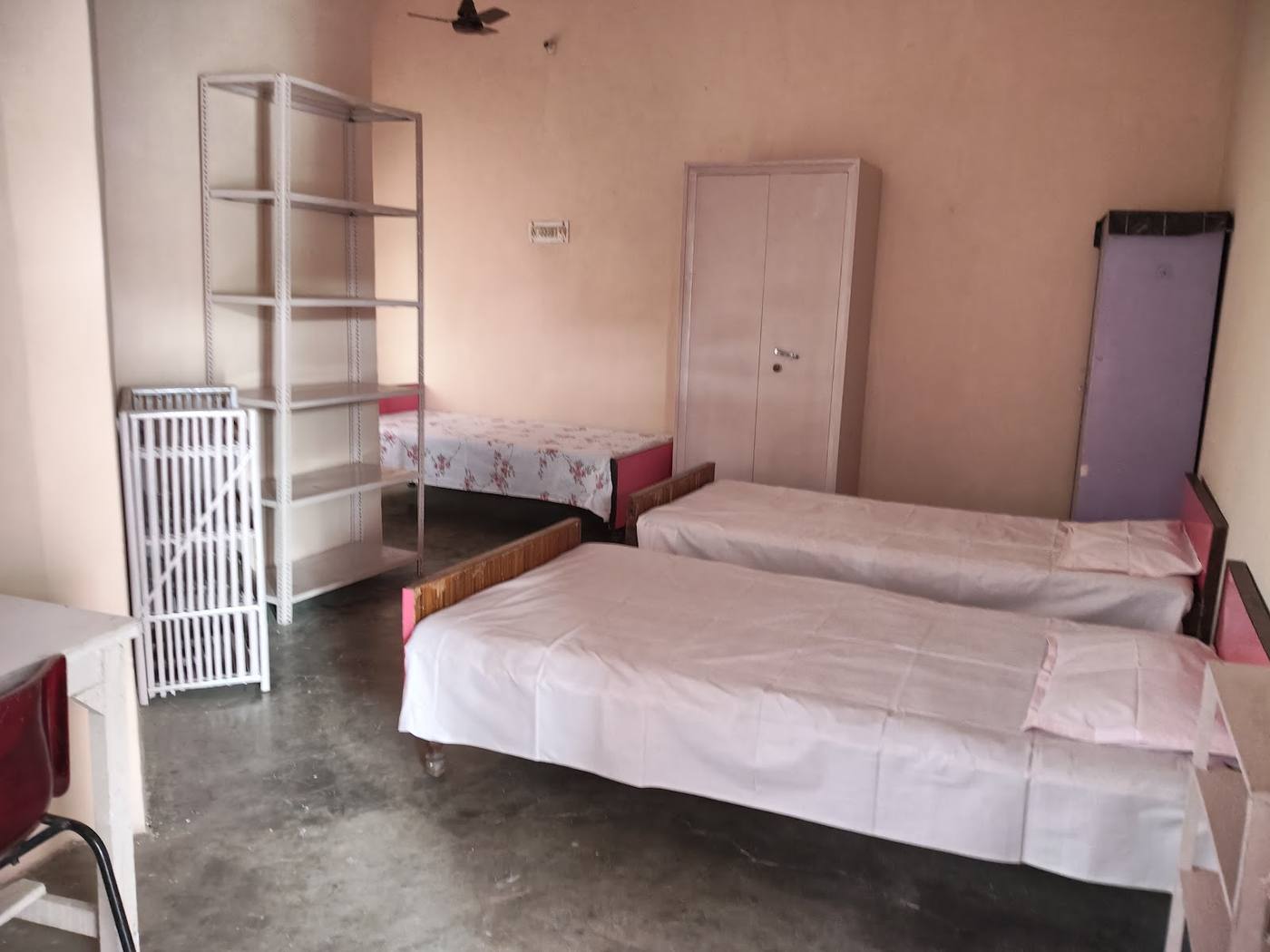 Room with three beds, open shelves and a wardrobe