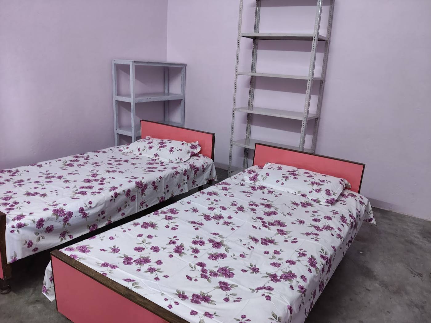 Twin room with two beds, floral sheets and open shelves
