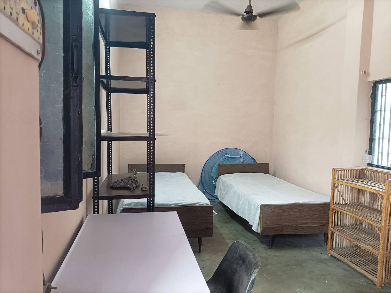 Twin room with two beds, shelves and a ceiling fan