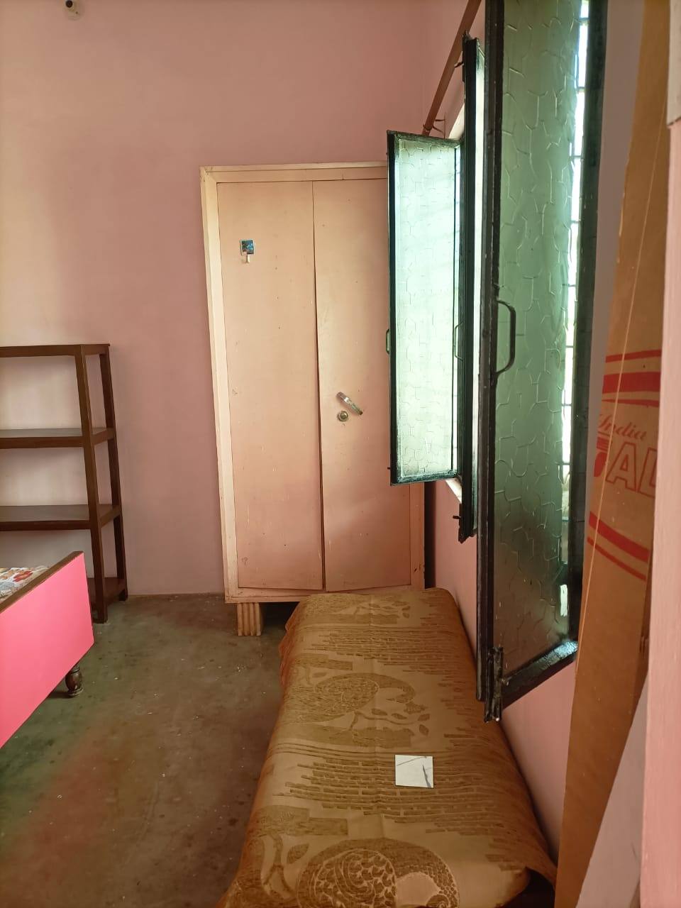 A bed beside a window, with a cupboard